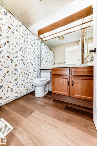 The bathroom features a wood vanity with a white countertop and a toilet - 4224 30 Street, Edmonton, AB - Indoor Photo Showing Bathroom
