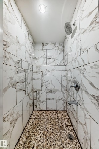The shower features white marble-effect tiling on the walls and a unique mosaic pebble-style floor - 4224 30 Street, Edmonton, AB - Indoor