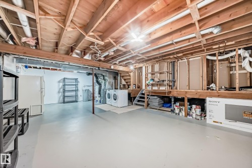 The basement features an unfinished ceiling with exposed wood joists, painted concrete flooring, and a dedicated laundry area with a washer and dryer - 4224 30 Street, Edmonton, AB - Indoor Photo Showing Basement