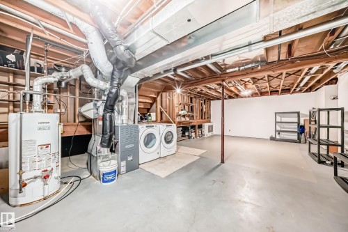 The property features a utility area with a water heater, furnace, and a washer and dryer set, all situated on a concrete floor - 4224 30 Street, Edmonton, AB - Indoor