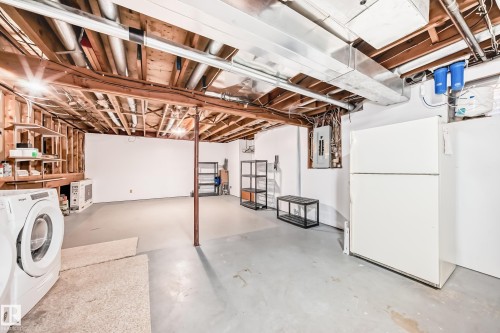 The property features a spacious basement with exposed wooden beams, a washer and dryer, and a refrigerator - 4224 30 Street, Edmonton, AB - Indoor Photo Showing Laundry Room