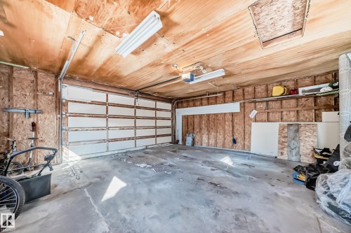 Spacious garage with a concrete floor, exposed wood paneling on the walls and ceiling, and overhead fluorescent lighting - 4224 30 Street, Edmonton, AB - Indoor Photo Showing Garage