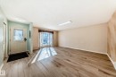 This property features light-colored wood flooring, a front door with a decorative glass panel, and large windows with natural light - 4224 30 Street, Edmonton, AB  - Indoor Photo Showing Other Room 