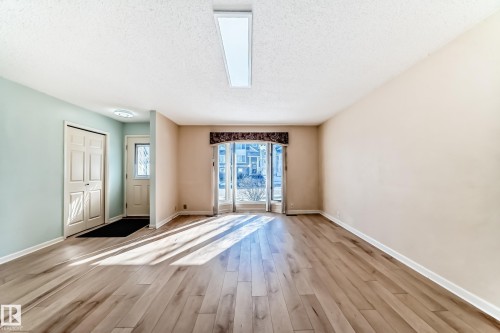 The living area features light-toned hardwood flooring, a ceiling-mounted light fixture, and a large glass door allowing for natural light - 4224 30 Street, Edmonton, AB - Indoor Photo Showing Other Room