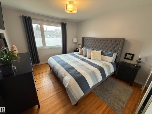 Room featuring wood-finish flooring, a double window with privacy film, and a ceiling-mounted light fixture - 11948 132 Street, Edmonton, AB - Indoor Photo Showing Bedroom