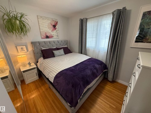 Hardwood flooring highlights this room, featuring a window with blinds, a built-in light fixture, and light-toned walls - 11948 132 Street, Edmonton, AB - Indoor Photo Showing Bedroom