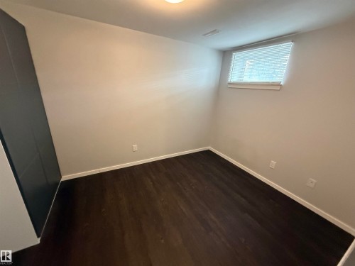 Room featuring dark wood-finish flooring, light neutral-toned walls, and a window with horizontal blinds - 11948 132 Street, Edmonton, AB - Indoor Photo Showing Other Room