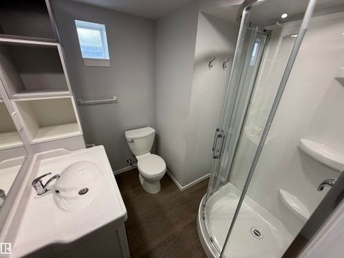 Full bathroom featuring a corner shower with glass enclosure, single vanity with integrated sink, toilet, and a window with privacy glass - 11948 132 Street, Edmonton, AB - Indoor Photo Showing Bathroom
