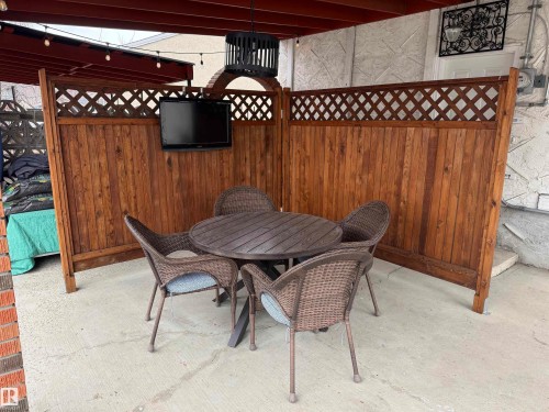 Covered patio featuring concrete flooring, wood paneling with lattice accents, and overhead string lighting - 11948 132 Street, Edmonton, AB -  With Exterior