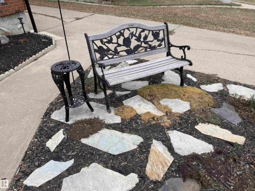 Landscaped garden bed featuring irregularly shaped stepping stones, dark mulch, and moss accents - 11948 132 Street, Edmonton, AB - Outdoor