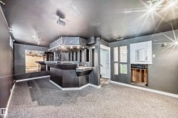 Recreational space featuring a built-in bar with multiple service stations, integrated lighting, and a textured countertop - 