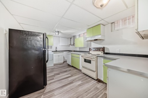 Kitchen featuring wood-finish flooring, light green cabinetry, white appliances, and gray countertops - 5204 112 Avenue, Edmonton, AB - Indoor Photo Showing Kitchen