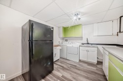 Utility room featuring wood-finish flooring, white walls, and a drop ceiling - 