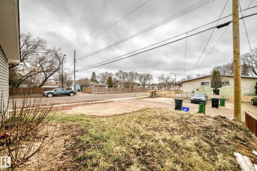 Street-facing property with partial siding visible on the left, an unpaved driveway, and a wood fence bordering the property - 5204 112 Avenue, Edmonton, AB - Outdoor