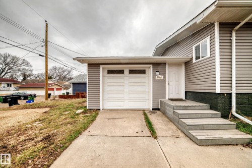 Siding exterior with a white garage door featuring transom windows - 5204 112 Avenue Nw, Edmonton, AB - Outdoor