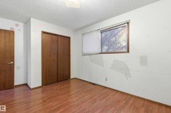 Bedroom featuring wood-finish flooring, a window with horizontal blinds, and a built-in double-door closet with wood-finish doors - 