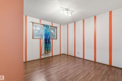 Interior space featuring wood-finish flooring, white walls with vertical orange stripes, and a window with wood trim - 