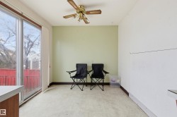 Spacious room featuring light-colored carpeting, a ceiling fan with light fixture, and a large sliding glass door - 