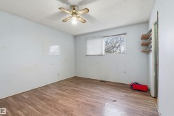 Interior room featuring wood-finish flooring, a window with blinds, and a ceiling fan with integrated lighting - 