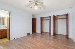 Spacious room featuring wood-finish flooring, a ceiling fan, and two wardrobes with bi-fold doors - 
