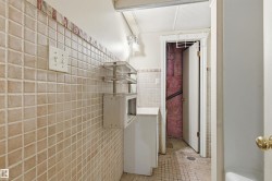 Beige square tile flooring and wall covering with a decorative border - 