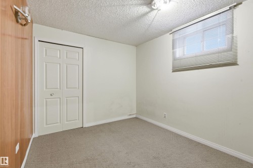 Neutral-toned carpeting grounds this room featuring a window with blinds, bi-fold closet doors, and wood-finish wall paneling - 11211 77 Avenue, Edmonton, AB - Indoor Photo Showing Other Room