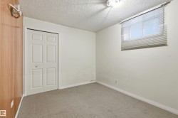 Neutral-toned carpeting grounds this room featuring a window with blinds, bi-fold closet doors, and wood-finish wall paneling - 