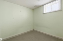 Interior room featuring a single window with blinds, light green walls, and neutral floor covering - 