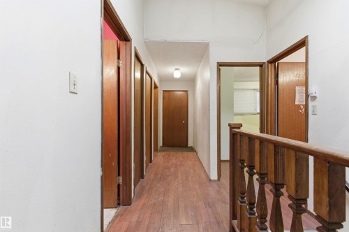 Hallway featuring wood-finish flooring, white painted walls, and multiple brown panel doors - 11211 77 Avenue, Edmonton, AB - Indoor Photo Showing Other Room