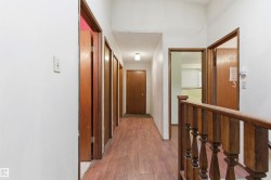 Hallway featuring wood-finish flooring, white painted walls, and multiple brown panel doors - 