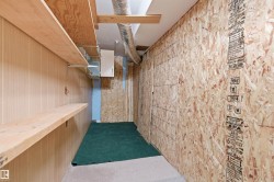 Utility space featuring wall-mounted shelving, wood-paneled walls, exposed ductwork, and oriented strand board wall construction - 