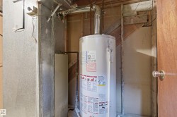 Water heater installation with visible plumbing lines and ventilation ductwork - 
