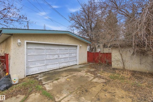 Attached garage with a panel garage door, stucco exterior, and wall-mounted exterior lighting - 11211 77 Avenue, Edmonton, AB - Outdoor