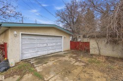 Attached garage with a panel garage door, stucco exterior, and wall-mounted exterior lighting - 