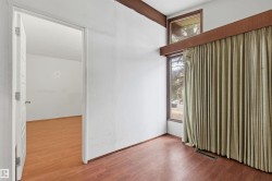 Room featuring wood-finish flooring, white walls, and a recessed ceiling vent - 