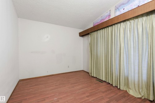Interior room featuring wood-finish flooring, white walls, and a large window with full-length drapes - 11211 77 Avenue, Edmonton, AB - Indoor Photo Showing Other Room