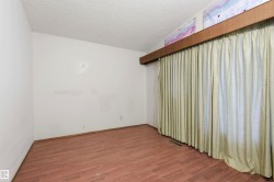 Interior room featuring wood-finish flooring, white walls, and a large window with full-length drapes - 
