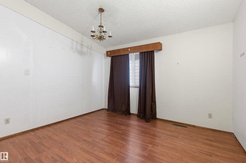 Room featuring wood-finish flooring, a textured ceiling, and a traditional chandelier - 11211 77 Avenue, Edmonton, AB - Indoor Photo Showing Other Room