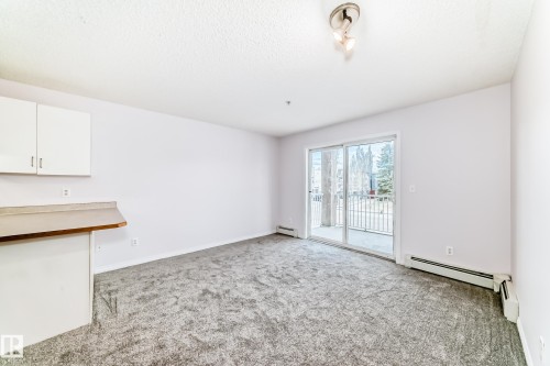 Spacious room featuring gray textured carpeting and white painted walls - 218 10535 122 Street, Edmonton, AB - Indoor Photo Showing Other Room
