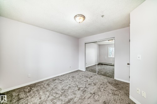 Bedroom featuring gray carpeting, white walls, and a ceiling-mounted light fixture - 218 10535 122 Street, Edmonton, AB - Indoor Photo Showing Other Room
