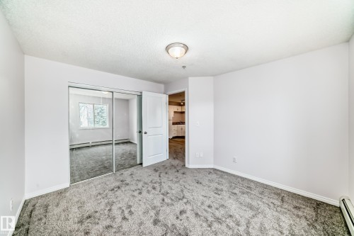 Spacious room with plush gray carpeting and white baseboards - 218 10535 122 Street, Edmonton, AB - Indoor Photo Showing Other Room