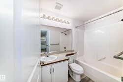 Bathroom featuring a white vanity with an integrated sink, a light-colored countertop, and a large wall mirror - 