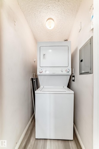 Dedicated laundry area featuring a stacked washer and dryer unit - 218 10535 122 Street, Edmonton, AB - Indoor Photo Showing Laundry Room