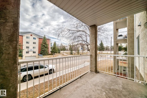 Private balcony featuring concrete flooring, white metal railings, and textured stucco columns - 218 10535 122 Street, Edmonton, AB - Outdoor With Exterior
