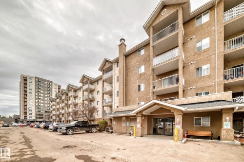 Multi-story residential building featuring stucco facade, individual balconies with white railings, and a prominent covered entryway - 218 10535 122 Street, Edmonton, AB - Outdoor With Facade