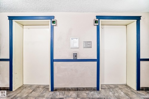 Dual elevators featuring classic blue trim and contemporary call buttons - 218 10535 122 Street, Edmonton, AB - Indoor Photo Showing Other Room