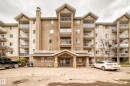 Multi-story building featuring individual balconies with white railings, a prominent central entrance with an awning, and a textured stucco exterior - 218 10535 122 Street, Edmonton, AB  - Outdoor With Facade 