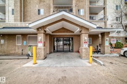 Building entrance featuring an overhead portico with soffit lighting and a dark shingle roof - 