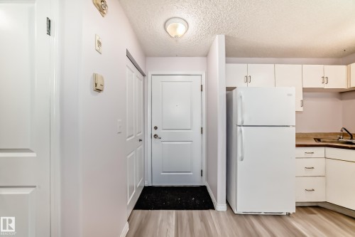 Entryway featuring a paneled door, light-colored walls, and wood-finish flooring - 218 10535 122 Street, Edmonton, AB - Indoor Photo Showing Kitchen