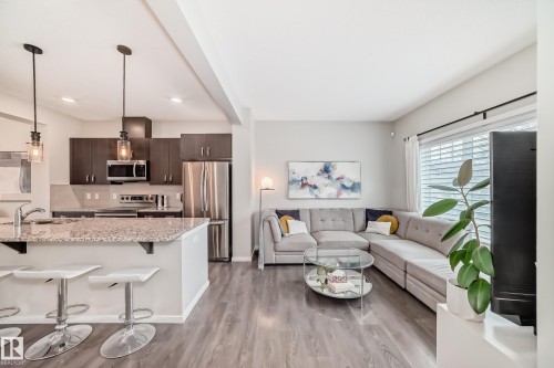 Open-concept living space featuring wood-finish flooring, a kitchen island with stone countertop, stainless steel appliances, dark wood cabinetry, and recessed lighting - 3278 Cherry Crescent, Edmonton, AB - Indoor Photo Showing Kitchen With Upgraded Kitchen